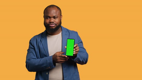 man showing thumbs down sign gesturing holding green screen phone