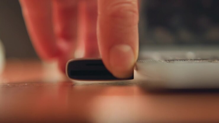 Closeup dongle near laptop edge, fingertips guiding small usb drive into port on wooden desk, shallow depth of field with warm bokeh, focused slow motion capturing precise insertion for media transfer