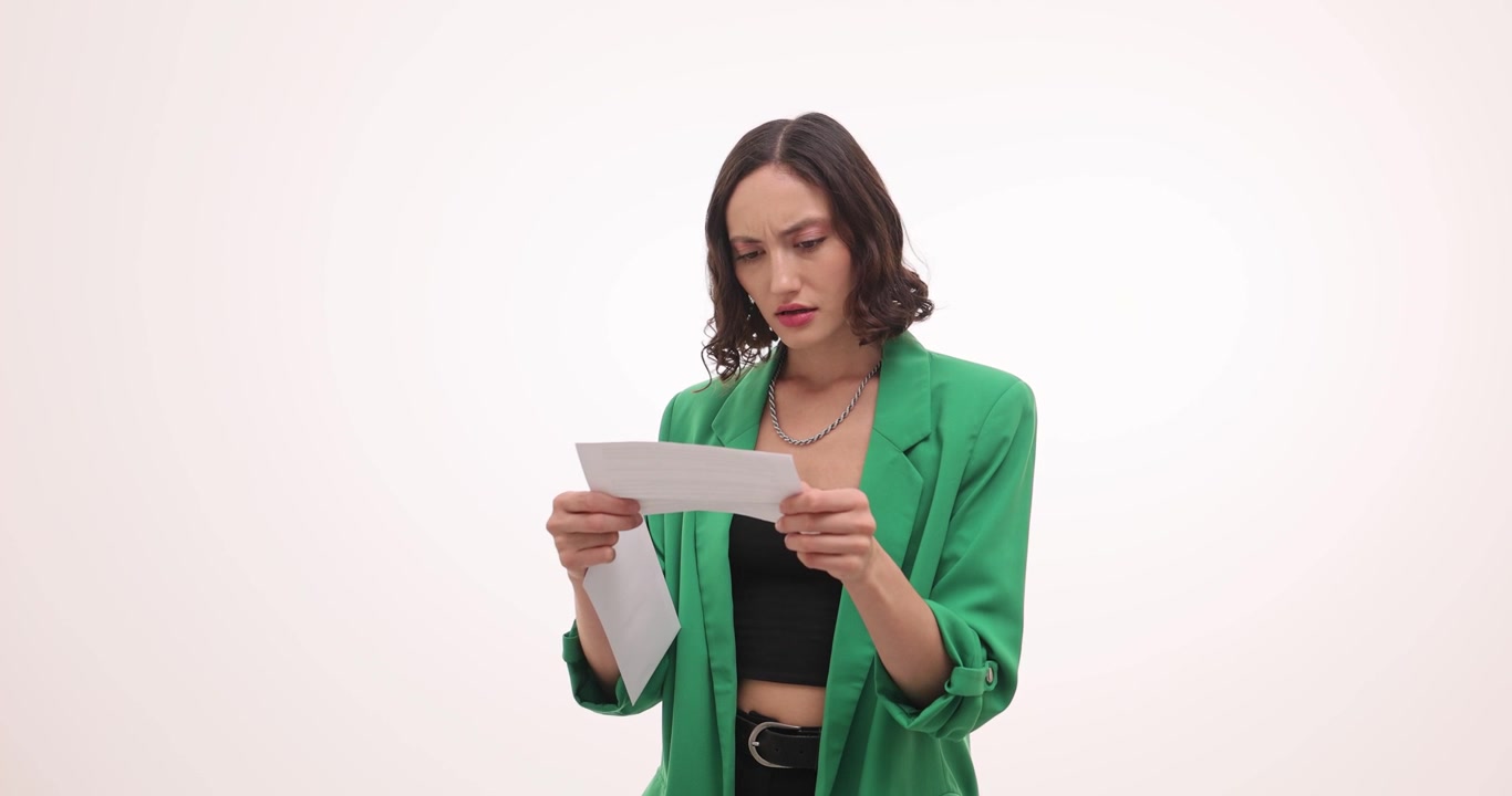 Mujer de verde abre un sobre mirando una carta con curiosidad