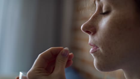 mujer caucásica de cabello rojo a punto de tomar pastillas y beber agua