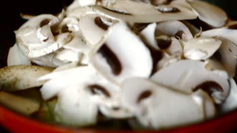 sliced mushrooms are frying in a hot red pan