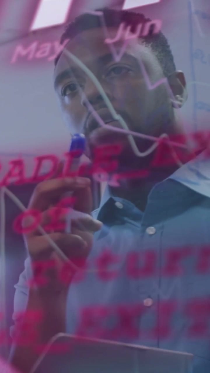 Vertical video: Man studying appearing charts on clear glass, using tablet and marker for business