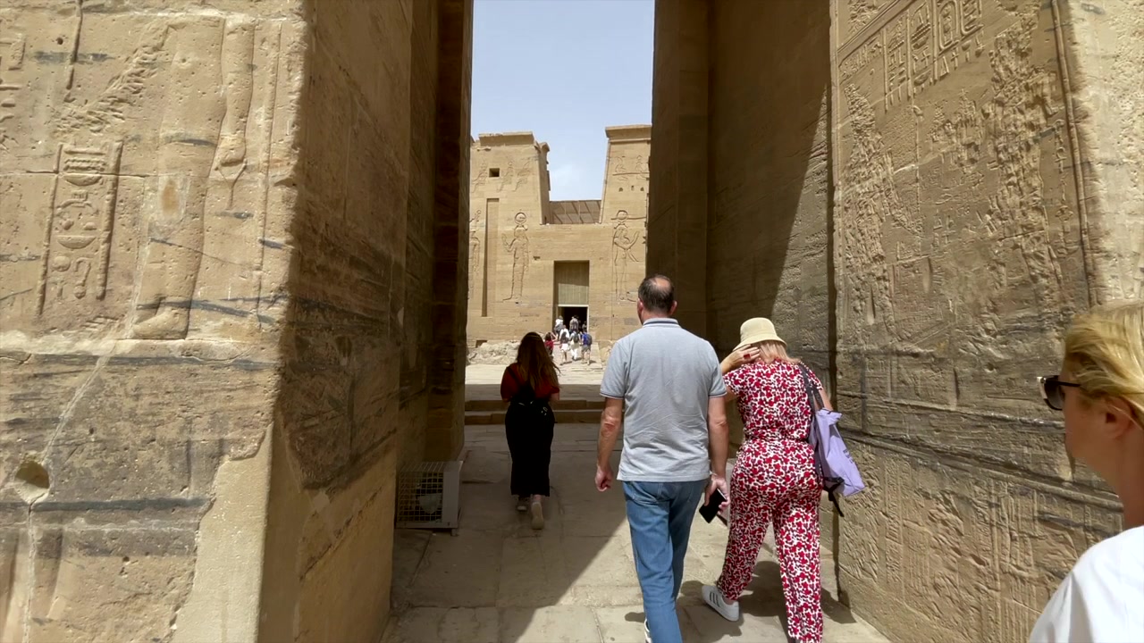 Turisti che camminano all'interno del tempio di Horus a Edfu, Egitto. Tempio egizio del dio Horus a Edfu. Monumento dell'antico Egitto. Visitatori che camminano tra le mura con geroglifici in un tempio religioso egizio.