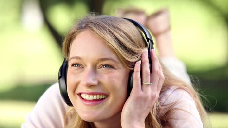 Happy-girl-lying-and-listening-to-music-in-the-park