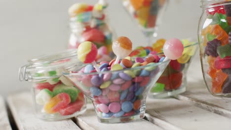 video of colourful various sweets in glass vessels on wooden table