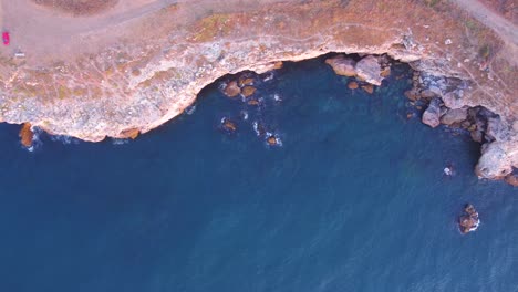 top down aerial view of waves splash against rocky seashore, background