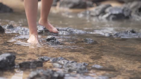 girl walking over black volcanic beach with small waves in fuerteventura, canary islands