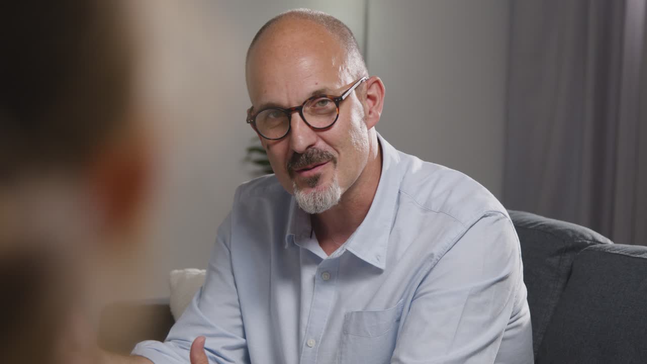 Mature Man Sitting On Sofa Talking With Female Counsellor About General Or Mental Health Issue 16