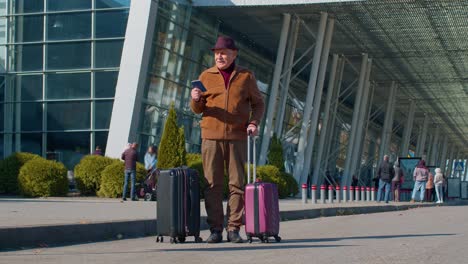 Elderly-retired-man-tourist-near-airport-terminal-celebrating-success,-winning-and-goal-achievemen