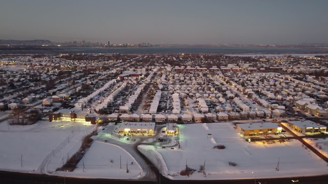 Drone panoramic pullback over dense suburban neighborhood at dusk lights on in Quebec, Canada, with a hazy sky