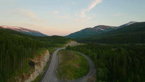 Experience-the-magical-midnight-sun,-Aerial-rising-over-e6-highway-in-Norway