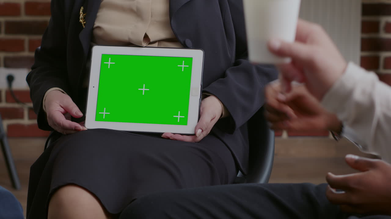 Close up of psychologist showing horizontal green screen on tablet at aa group meeting