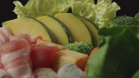 close up of a pot of shabu ingredients spinning around on the black background