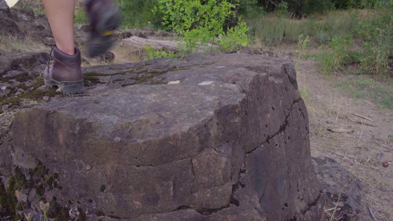 귀여운 힙스터 소녀가 바위 위로 올라가고 있다