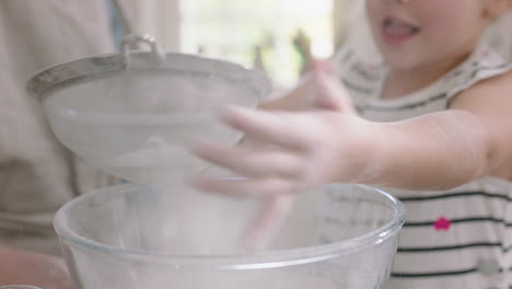 happy little girl helping mother bake in kitchen mixing ingredients sifting flour using sieve preparing recipe for cupcakes at home