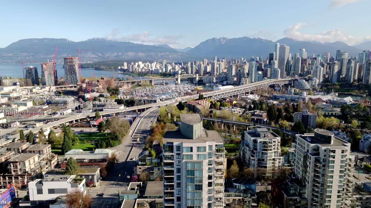 Modern Towers Overlook South Granville as the Granville Bridge Connects to Downtown Vancouver With Mountains Beyond in Vancouver, British Columbia, Canada - Pan Up Shot