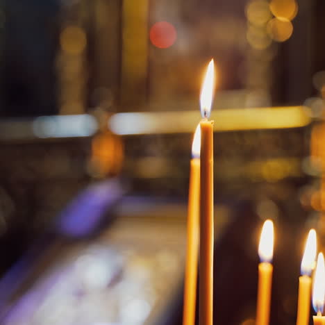 tranquil atmosphere of light candles burning brightly in the blurred background. wax candles are glowing in church.