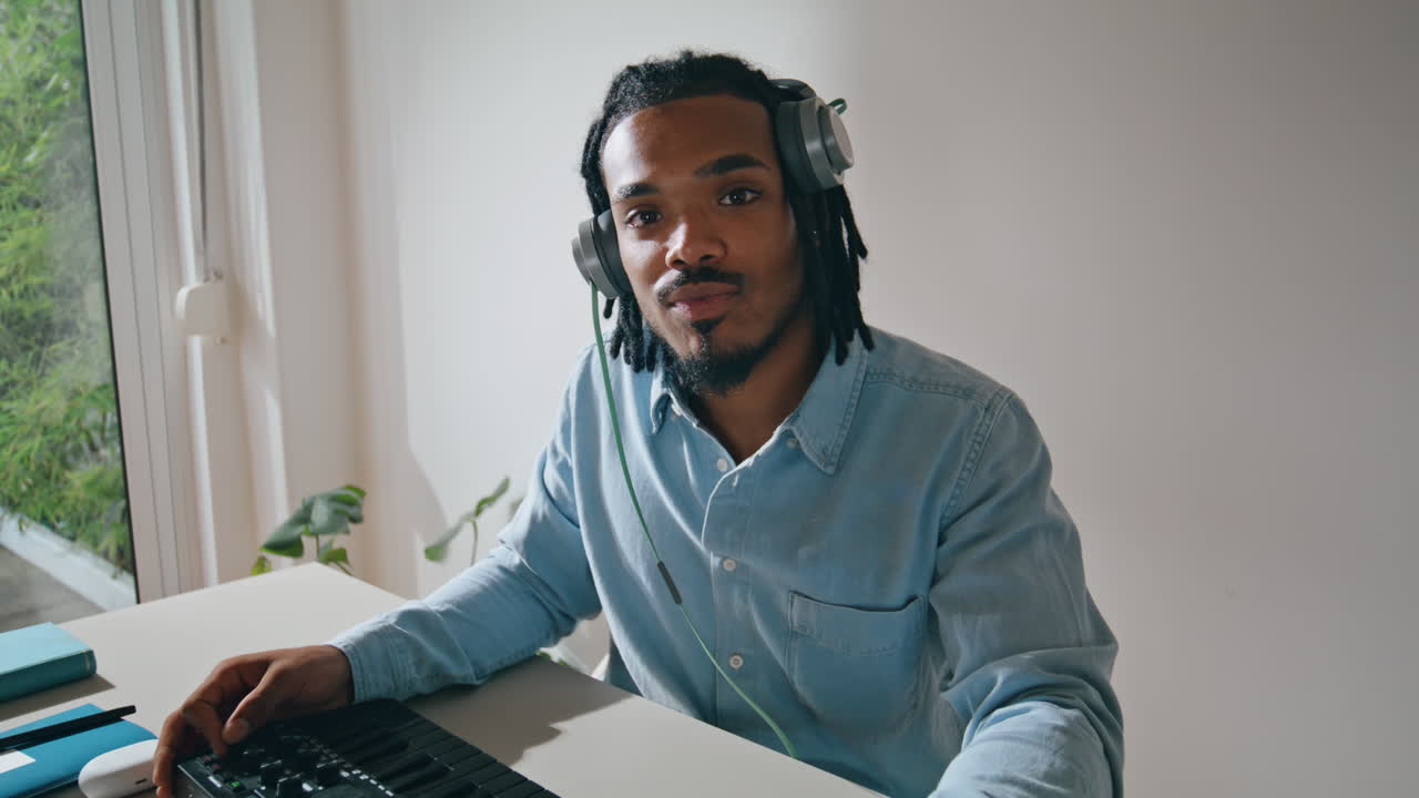 Dreadlocks man using console at table portrait. Sound producer smiling camera