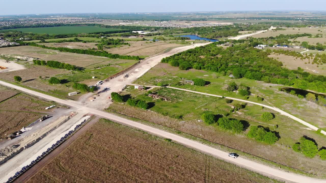 moviéndose hacia una gran extensión de carretera que se está construyendo a través del campo