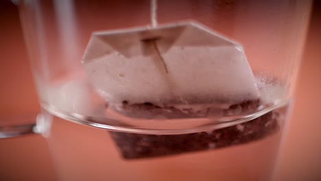 dipping organic tea bag in cup of hot water, steam all around