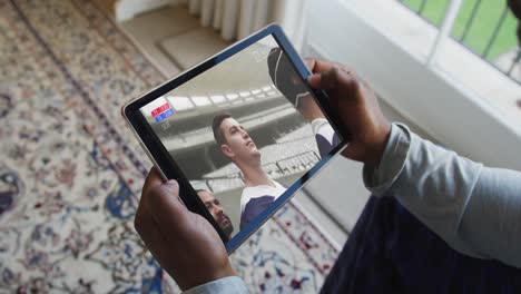 Composite-of-man-sitting-at-home-watching-rugby-match-on-tablet