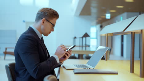 un hombre de negocios serio usando un teléfono inteligente tocando la pantalla digital de un teléfono moderno en la sala de reuniones de la oficina - toma trasera de la muñeca