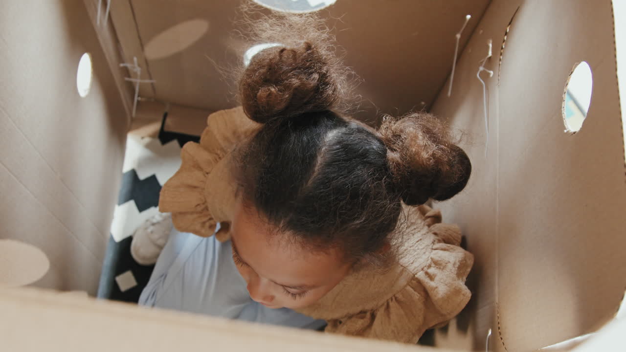 Cute Girl Sitting Inside Cardboard Rocket Ship