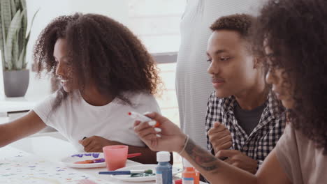 young adult black man and his two sisters making sign for a surprise party in the kitchen, close up