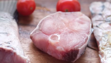 filete de pescado crudo en una tabla de corte de madera con tomates