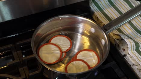 putting canning jar lids in hot water to heat them up to seal to the jars - zoom out dynamic motion