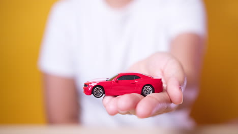 camión de juguete en la mano del concepto de mujer para seguros, compra, alquiler, combustible o costos de servicio y reparación