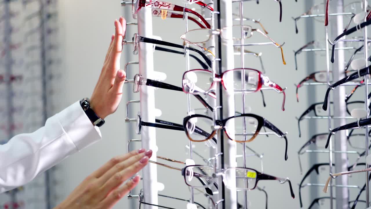 Eyesight concept. Woman standing near the stand with stylish eyeglasses in the optical store. Buyer choosing new glasses in the shop.