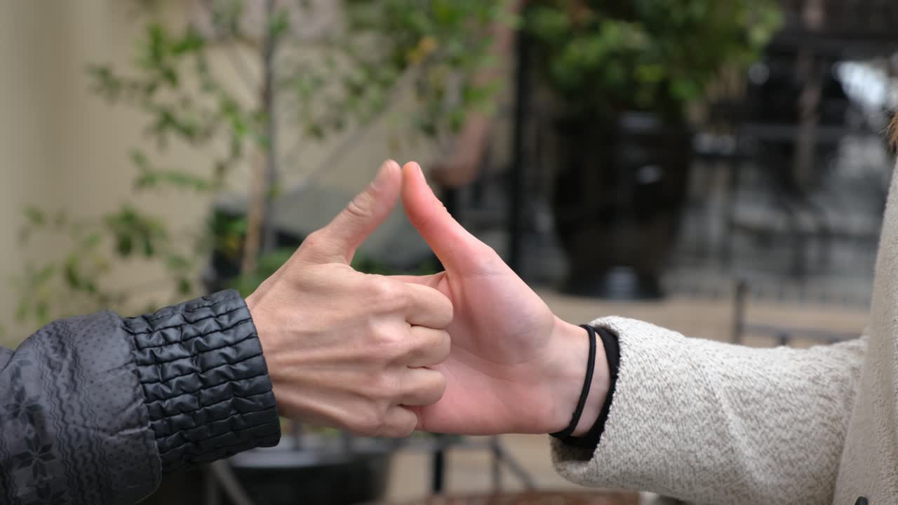 two women playing Thumb war finger wrestling. Close up of hands having a thumb war.