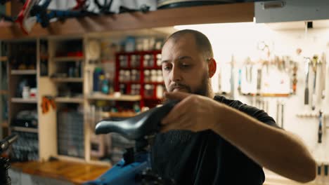 Handsome-bearded-master-repairing-a-bicycle-in-atmospheric-workshop