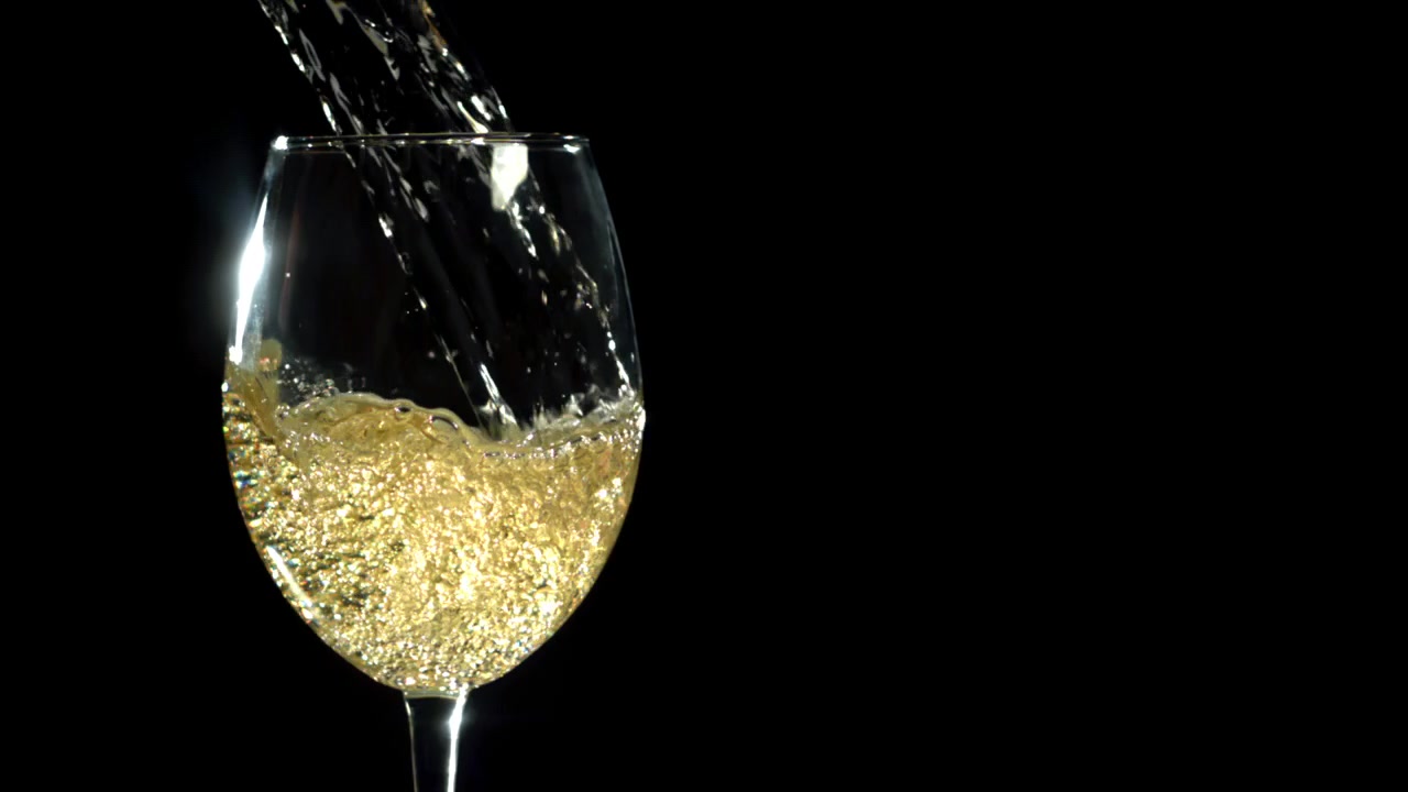 Vino bianco dorato che si versa in un bicchiere trasparente su sfondo nero
