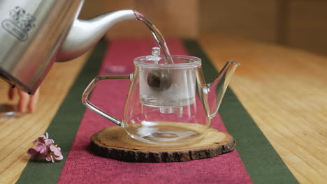 pouring hot water into a glass teapot