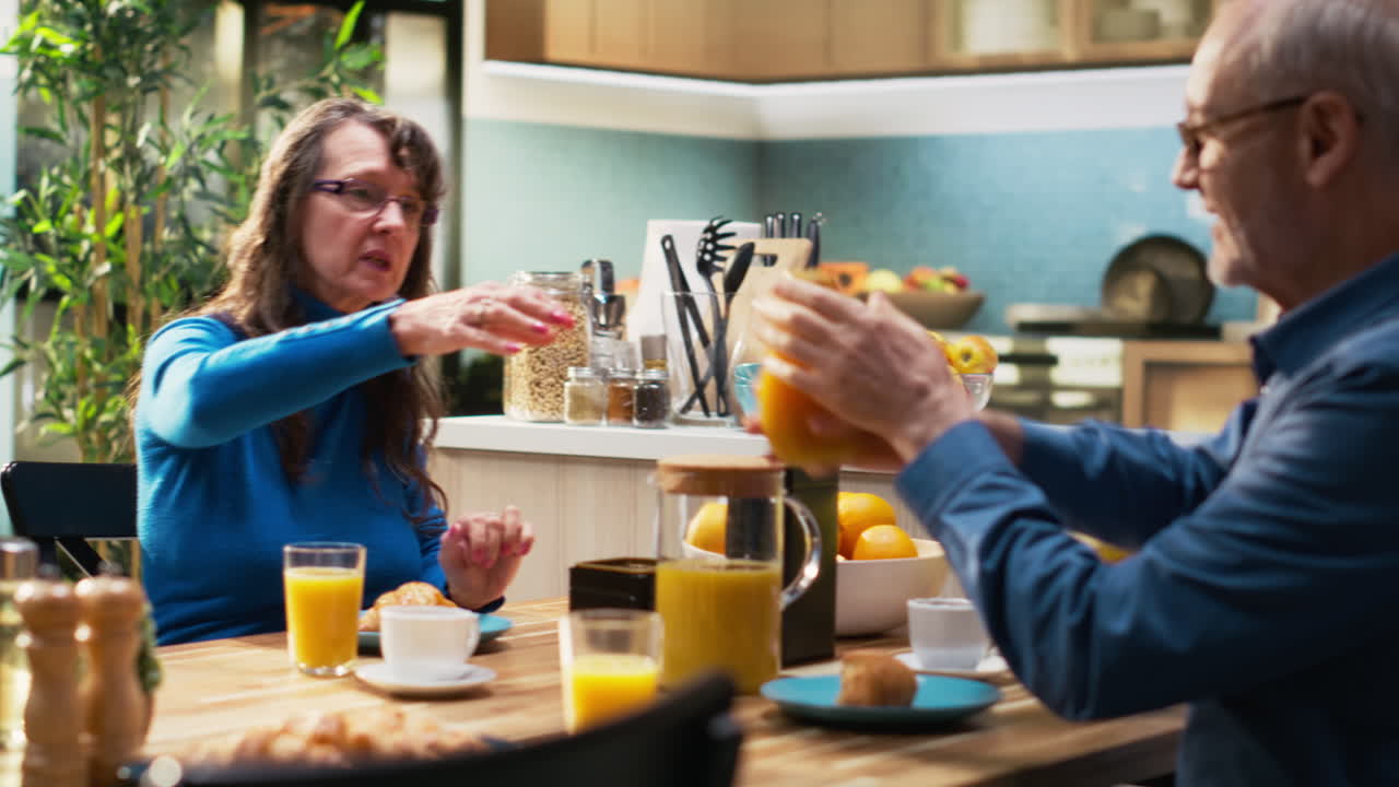 Aged husband and wife enjoy a weekend morning at the kitchen table