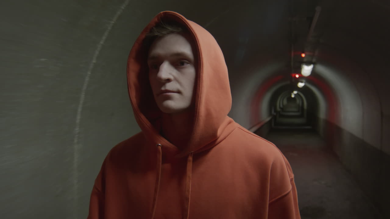 Boy in Hoodie Walking in Dark Tunnel