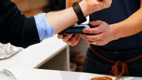 hand of customer making payment through smartwatch