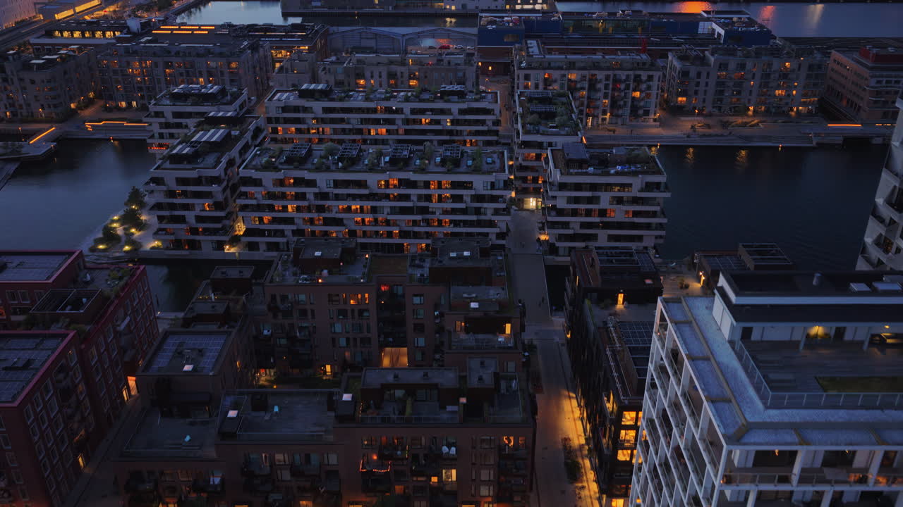 Aerial drone view of Orestad's residential district with illuminated modern apartment blocks at night in Copenhagen, Denmark