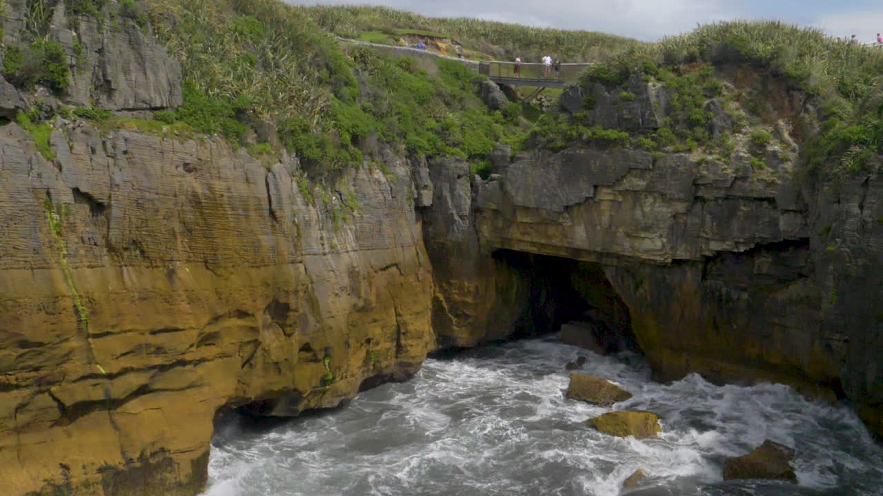 Slow Motion Wave in Sea cave with cliff above - Punakaiki, New Zealand