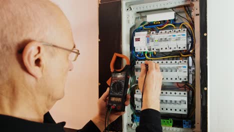 electricians hands testing current  electric in control panel. electrician engineer work  tester measuring  voltage and current of power electric line in electical cabinet control.