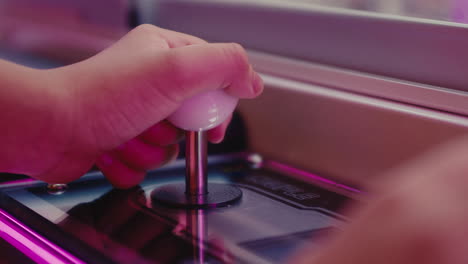 close up of young kid controlling a joystick while playing arcade video game