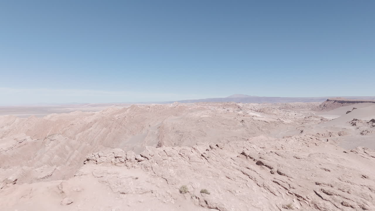 Drone shot flying over the dry sand desert mountains in San Pedro de Atacama Chile South America on a blue sky day near Mars Valley and Valley de la Luna LOG