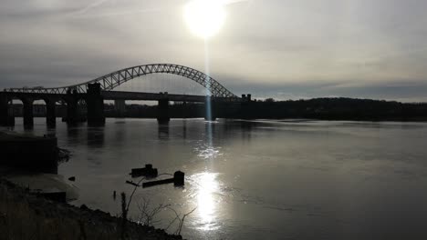 sunrise over industrial shipwreck in shimmering river mersey under silver jubilee bridge