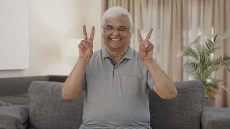 happy indian old man showing victory sign