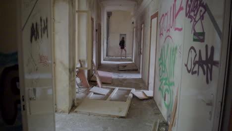 Long-Corridor-in-an-abandoned-Building-with-a-Girl-walking-at-the-end-of-it-in-Slow-Motion