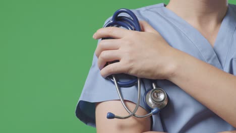close up of male doctor's hand holding a stethoscope while crossing his arms on green screen background in the hospital