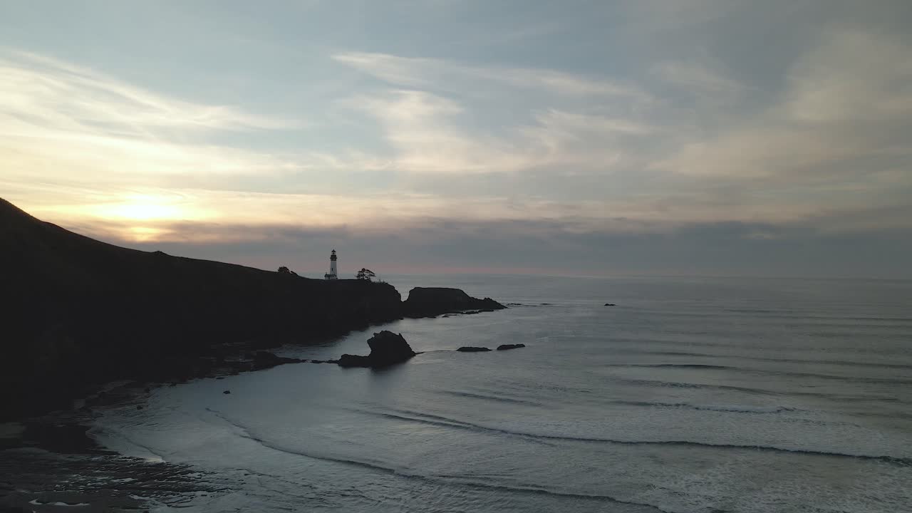 um drone a voar em direcção ao farol de yaquina head, ao largo da costa de newport, oregon.
