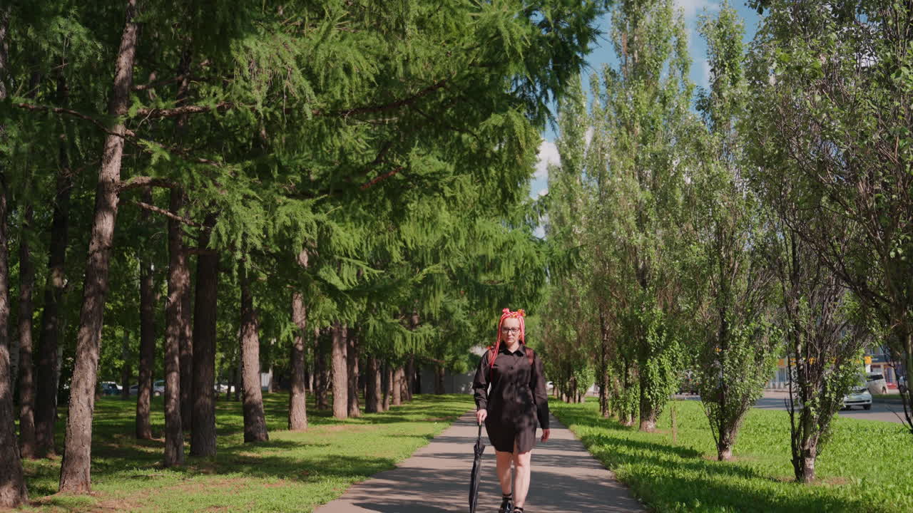 mujer con paraguas, empresaria sosteniendo un paraguas en una calle arbolada de la ciudad durante el verano, mujer paseando con un paraguas por un bulevar urbano soleado bordeado de árboles durante los meses cálidos